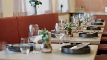 Gros plan sur des tables dressées avec style dans le restaurant RUUF, avec de la vaisselle sombre et des vases de fleurs