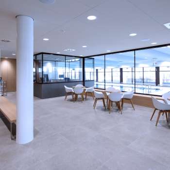 Coin salon lumineux dans la piscine intérieure de Triesen avec vue sur la piscine à travers la façade vitrée.