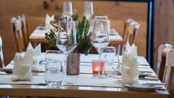 Gros plan sur une table joliment dressée avec des verres, des couverts et une petite décoration végétale