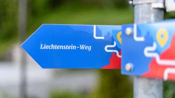 Panneau indicateur bleu avec l'inscription « sentier du Liechtenstein » au design moderne.