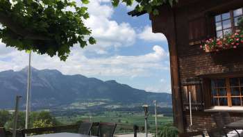 Bâtiment traditionnel avec terrasse ensoleillée et panorama de montagne en arrière-plan