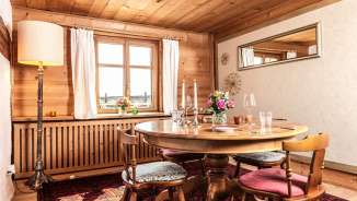 Table en bois dressée avec style dans un Stübli traditionnel du Liechtenstein avec vue sur les montagnes à travers la fenêtre