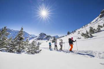 Groupe lors de randonnées en raquettes à travers le paysage enneigé du Schönberg près de Malbun sous un soleil d'hiver radieux.