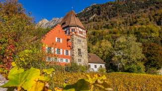 La Maison Rouge à Vaduz, au Liechtenstein, nichée dans un paysage automnal coloré et des vignobles au pied des montagnes.