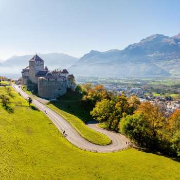 Château de Vaduz sur une colline avec vue sur la vallée du Rhin et les montagnes environnantes.