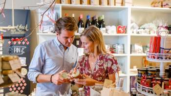 Un couple découvre des spécialités régionales dans la Hoi-Laden à Vaduz - découvrir de près des produits authentiques du Liechtenstein.
