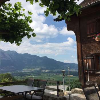 Bâtiment traditionnel avec terrasse ensoleillée et panorama de montagne en arrière-plan