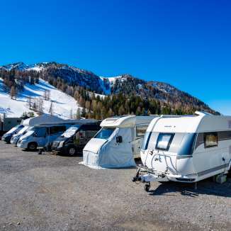 Camping-cars et caravanes sur un emplacement enneigé à Malbun avec vue sur les Alpes