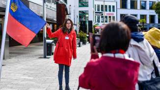 Une guide présente le drapeau du Liechtenstein lors d'une visite guidée dans le centre de Vaduz