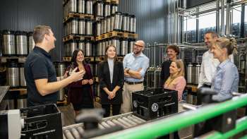 Groupe de visiteurs lors d'une visite guidée de l'entrepôt de fûts de la brasserie avec les explications d'un collaborateur de la brasserie.