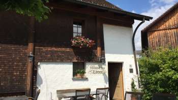 Auberge rustique avec façade en bois et fenêtres fleuries, entourée d'une nature verdoyante