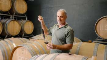 Harry Zech prélève du vin pour la dégustation dans une barrique à l'aide d'une pipette - vinification traditionnelle à Schaan.