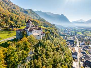 Vue du château de Vaduz au Liechtenstein avec des couleurs automnales, des montagnes et la vallée du Rhin en arrière-plan