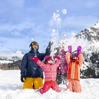 Une famille profite ensemble de la neige à Malbun - les enfants lancent joyeusement des boules de neige dans un décor de montagne hivernal.