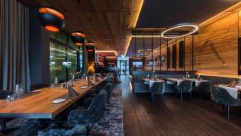 Salle de restaurant élégante avec des éléments d'éclairage modernes et des revêtements en bois sur les murs.