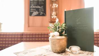 Détail d'une table dressée avec des cartes de menu, des fleurs et une décoration rustique