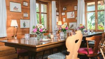 Salle de restaurant accueillante avec plafond en bois, table décorée avec soin et vue sur les fenêtres lumineuses
