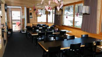 Salle de restaurant chaleureuse avec des murs en bois, une ambiance rustique et une décoration soignée au restaurant Schneeflucht Salle de restaurant chaleureuse avec des murs en bois, une ambiance rustique et une décoration soignée au restaurant Schneeflucht