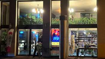 Vue extérieure éclairée du cinéma Skino à Schaan la nuit, avec de grandes baies vitrées et une atmosphère accueillante.