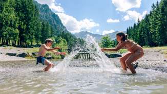 Les enfants barbotent dans le lac Gänglesee près de Steg, entouré de forêts et de montagnes - découverte de la nature et rafraîchissement au Liechtenstein