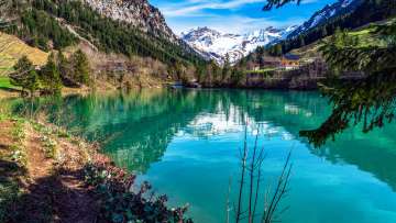 Lac de montagne cristallin lac Gänglesee à Steg, Liechtenstein - encadré de forêts, de montagnes et d'un vert printanier frais