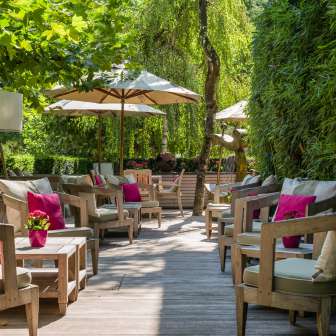 Groupe de sièges confortables avec coussins, plantes et parasols sur la terrasse du Park Hotel Sonnenhof à Vaduz, Liechtenstein