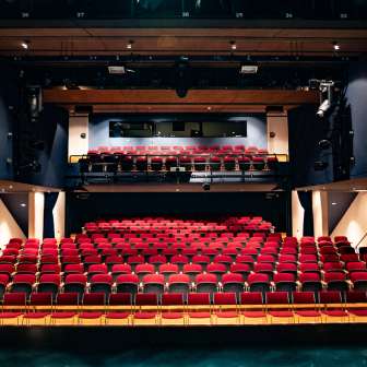 Vue depuis la scène sur les rangées de sièges rouges et la technique d'éclairage dans la salle de spectacle moderne du TAK Theater Liechtenstein