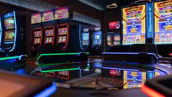Vue de la zone moderne des machines à sous du Casino Admiral Triesen, avec ses machines à sous à l'éclairage coloré.