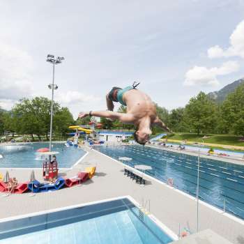 unge saute en salto du plongeoir d'un mètre dans le bassin de la piscine de Mühleholz - la joie estivale à l'état pur.