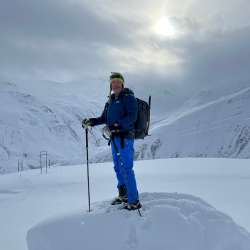 Randonnée en raquettes à neige avec le guide de randonnée Nikolaus Büchel Nikolaus Büchel se tient debout avec son sac à dos et ses bâtons lors d'une randonnée en raquettes dans un paysage hivernal de haute montagne