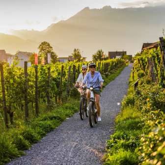 Deux cyclistes dans les vignobles du Liechtenstein au coucher du soleil - vélo électrique avec vue sur les Alpes et les vignes