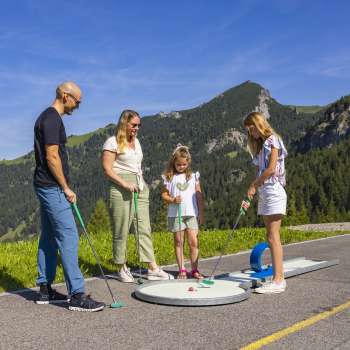  Une famille joue au minigolf ensemble dans les montagnes de Malbun sous un soleil radieux