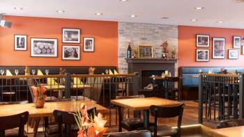Salle de restaurant chaleureuse au New Castle, avec ses couleurs chaudes, sa cheminée et ses tables en bois élégantes