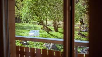 Vue depuis le balcon de la maison d'hôtes du camping Mittagsspitze sur la verdure, les arbres et la pelouse.