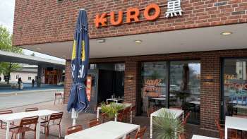 Vue extérieure du restaurant Kuro avec des tables de vin à l'extérieur au premier plan Vue extérieure du restaurant Kuro avec des tables de vin à l'extérieur au premier plan
