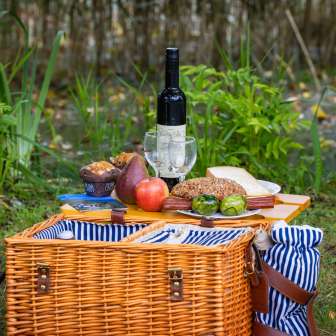 Panier pique-nique avec des spécialités régionales, du pain frais, des fruits et du vin, soigneusement disposés sur une prairie en pleine nature.