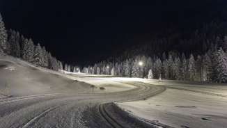 Piste de ski de fond éclairée à Steg la nuit, niché dans des forêts enneigées