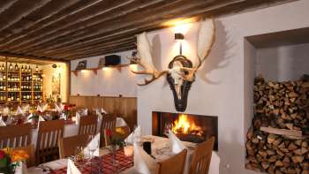 Ambiance chaleureuse du restaurant avec poutres en bois rustiques et cheminée