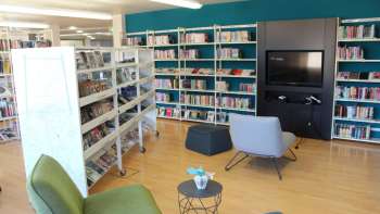 Coin lecture confortable dans la Bibliothèque nationale du Liechtenstein avec fauteuils et mur multimédia entre de hautes étagères de livres