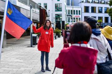 Une guide présente le drapeau du Liechtenstein lors d'une visite guidée dans le centre de Vaduz