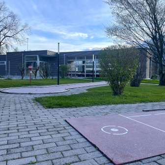 Minigolf avec plusieurs pistes sur un espace vert bien entretenu entre Schaan et Vaduz, avec en arrière-plan des bâtiments modernes et des arbres.