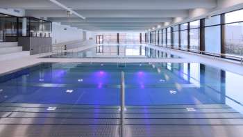 Piscine intérieure moderne à Triesen avec bassin éclairé et grande façade vitrée.
