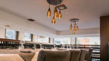 Espace de restauration à l'aménagement moderne avec vue sur la baie vitrée et lampes suspendues de style.