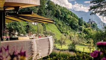 Terrasse ensoleillée avec des fleurs épanouies et des tables élégamment décorées avec vue sur la vallée