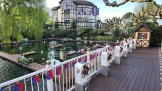 Bateaux télécommandés dans le bassin d'eau d'Europa-Park, entourés de maisons à colombages et d'arbres printaniers