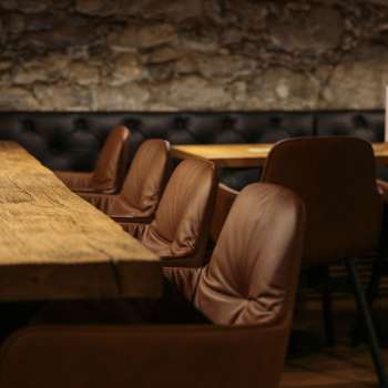 Détail d'une table en bois avec de confortables chaises en cuir dans l'agréable coin salon du WY Weinbar.