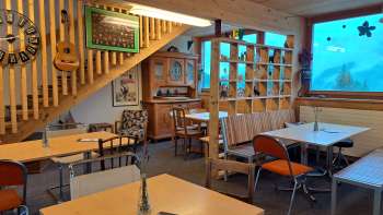 Salle de restaurant avec baie vitrée et décoration - Tables et chaises dans un espace ouvert avec de grandes fenêtres et vue sur l'extérieur verdoyant.