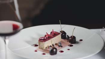Dessert élégant sur une assiette blanche, décoré de cerises et de chocolat