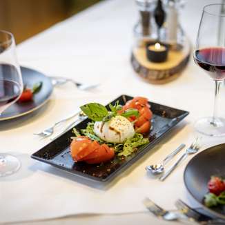 Salade fraîche de tomates et mozzarella avec vin rouge sur une table dressée au JUFA Hotel Malbun