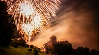 Feu d'artifice au-dessus du château de Vaduz - ambiance festive au Liechtenstein la nuit Château de Vaduz au Liechtenstein de nuit avec un grand feu d'artifice dans le ciel - photo d'ambiance avec lumière et brouillard